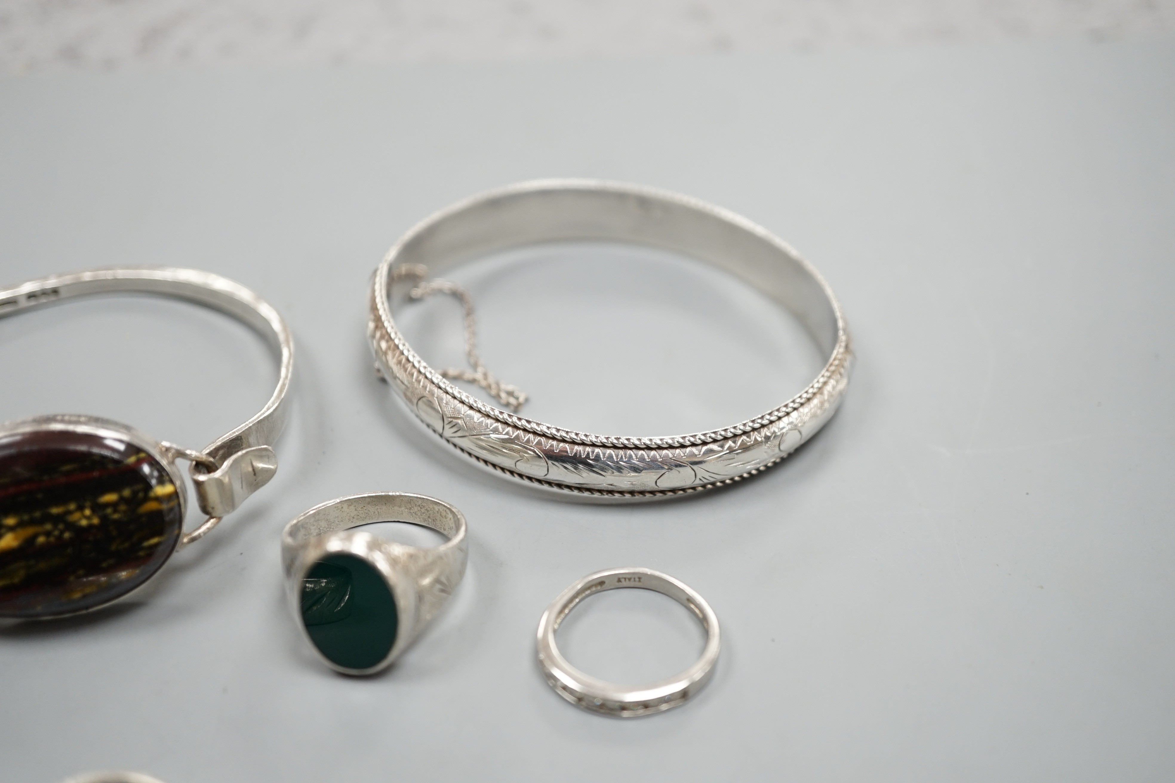 A 1970's silver and oval quartz set bangle, two other white metal bangles and three assorted rings.